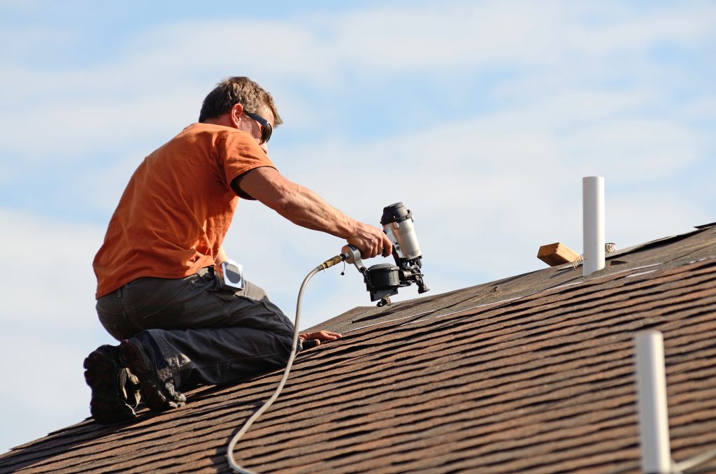 Building contractor putting the asphalt roofing on a large commercial apartment building development